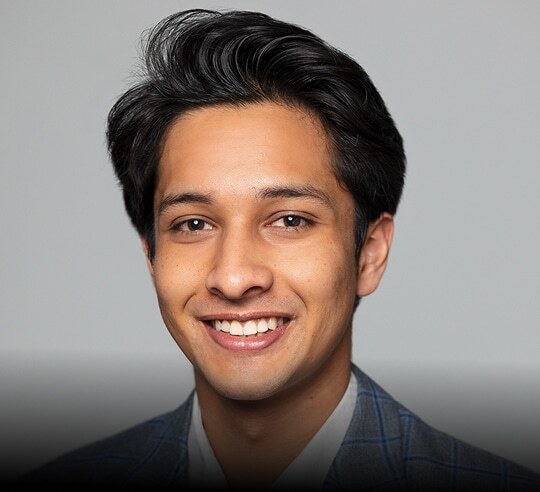 Smiling Financeable student in a dark suit against a gray background